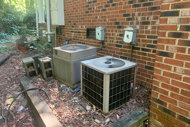 Two old air conditioners outside of home