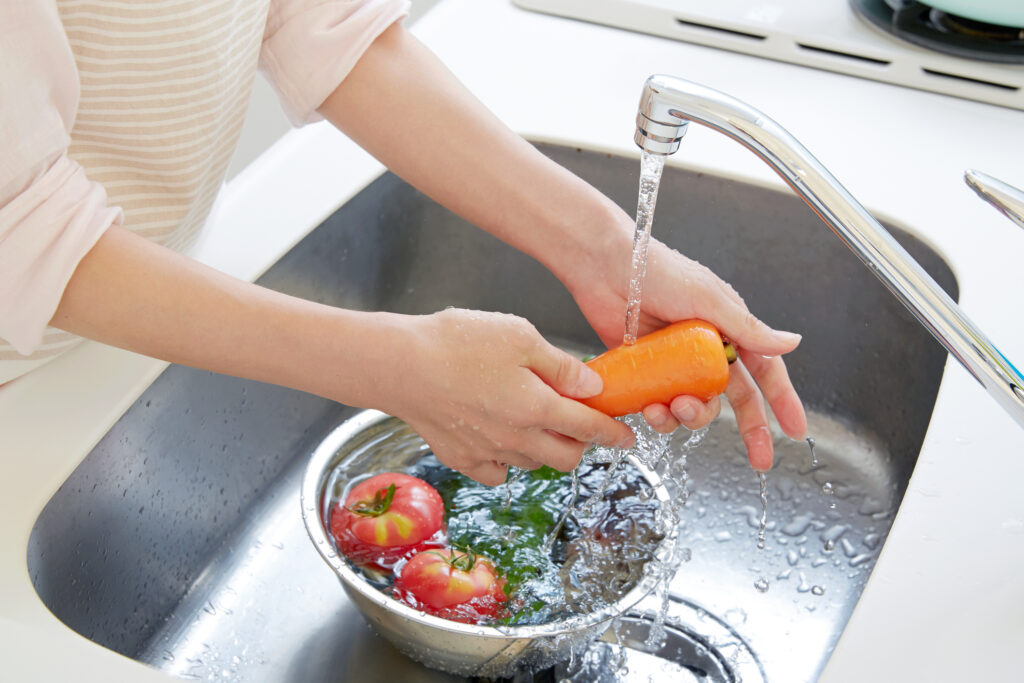 close up of faucet and hands washing the vegetables